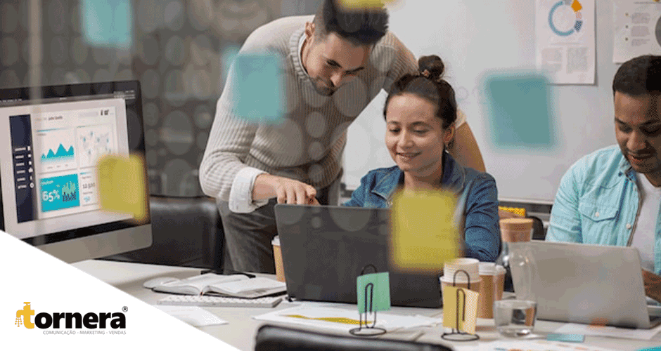 Um grupo de pessoas sentadas ao redor de uma mesa trabalhando em notebook