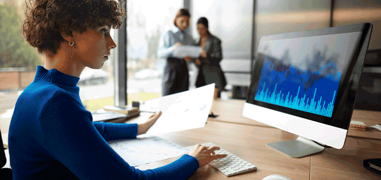 Uma mulher sentada em uma mesa usando um computador