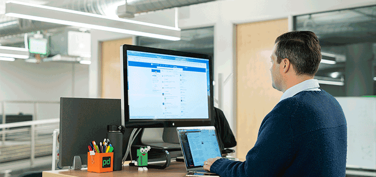 Um homem sentado em uma mesa usando um computador mexendo no LinkedIn