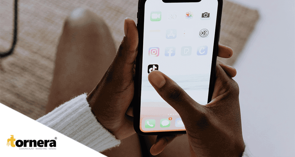 Uma pessoa segurando um celular na mão e abrindo o TikTok