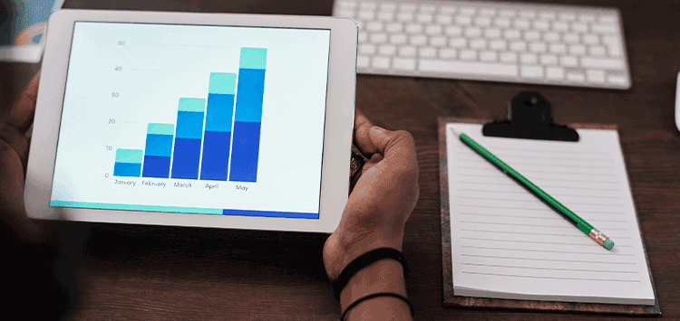 Uma pessoa segurando um tablet com um gráfico de barras