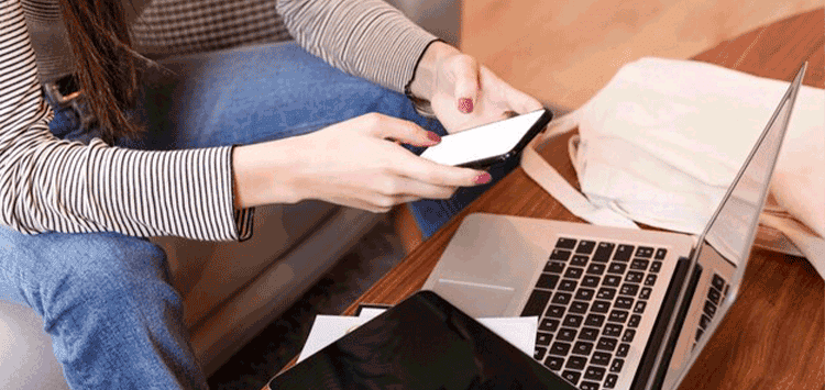 Uma mulher sentada à mesa com um notebook e um celular
